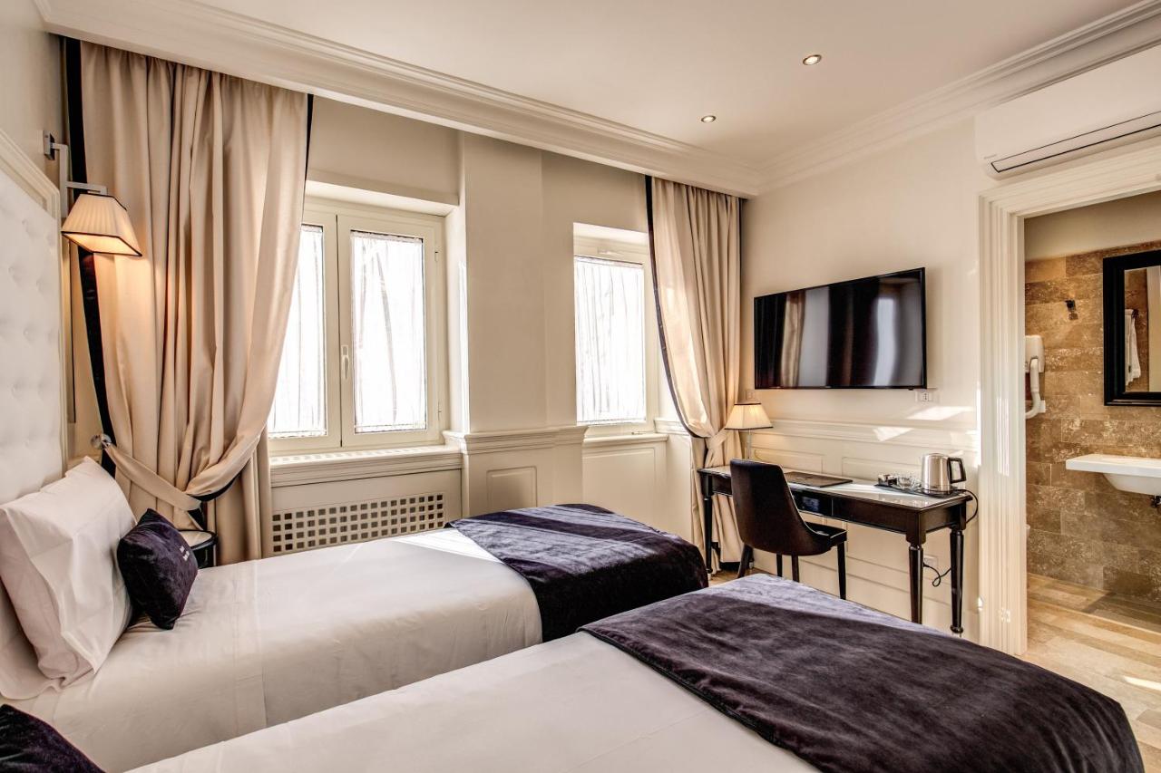 een hotelkamer met twee bedden en een bureau bij Hotel Domus Mea in Rome