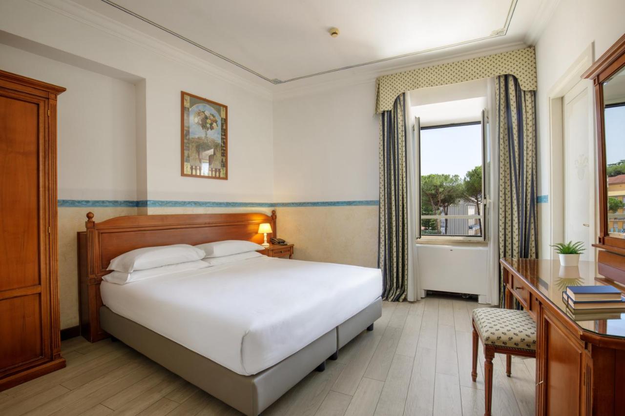 een slaapkamer met een bed, een bureau en een badkuip bij Hotel Alessandrino in Rome