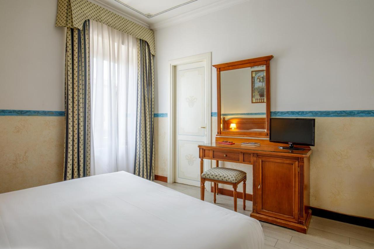 een slaapkamer met een bed en een bureau met een televisie bij Hotel Alessandrino in Rome