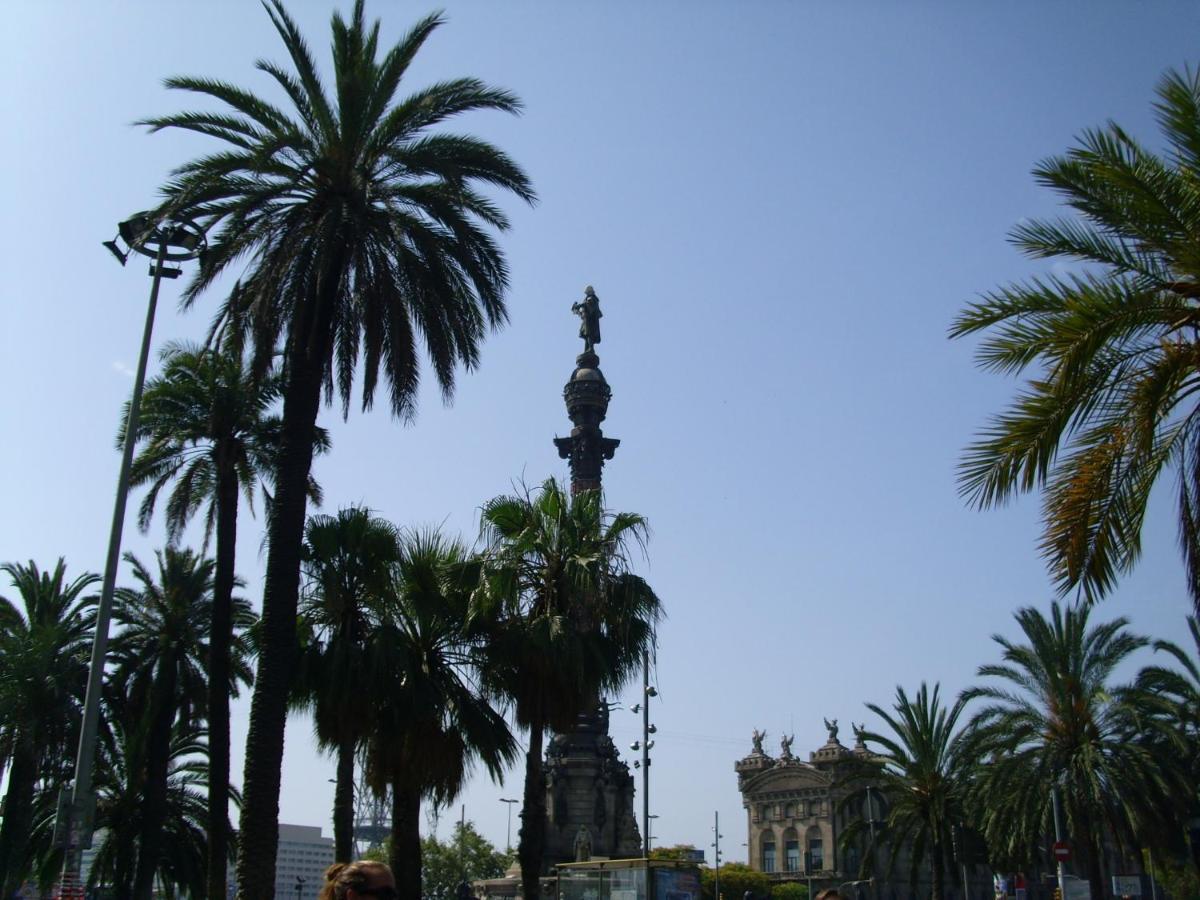 een monument met palmbomen voor een gebouw bij Hotel Cantón in Barcelona