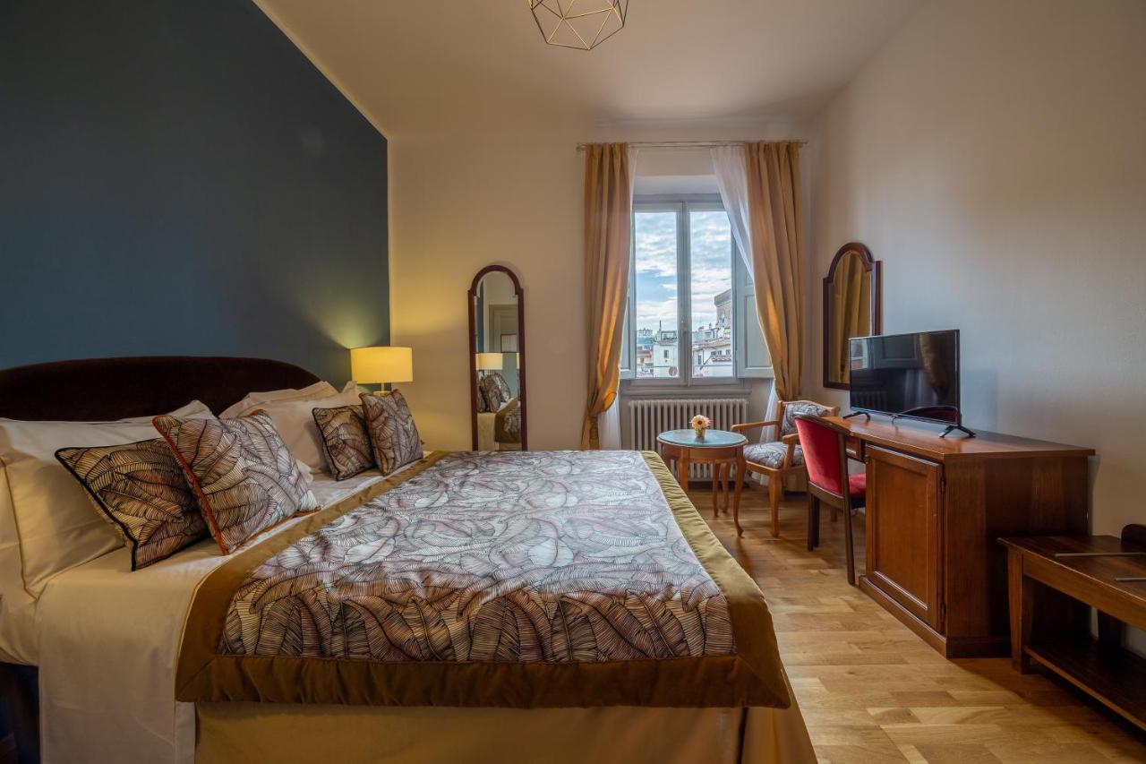 een slaapkamer met een bed, een bureau en een televisie bij Hotel Villani in Florence