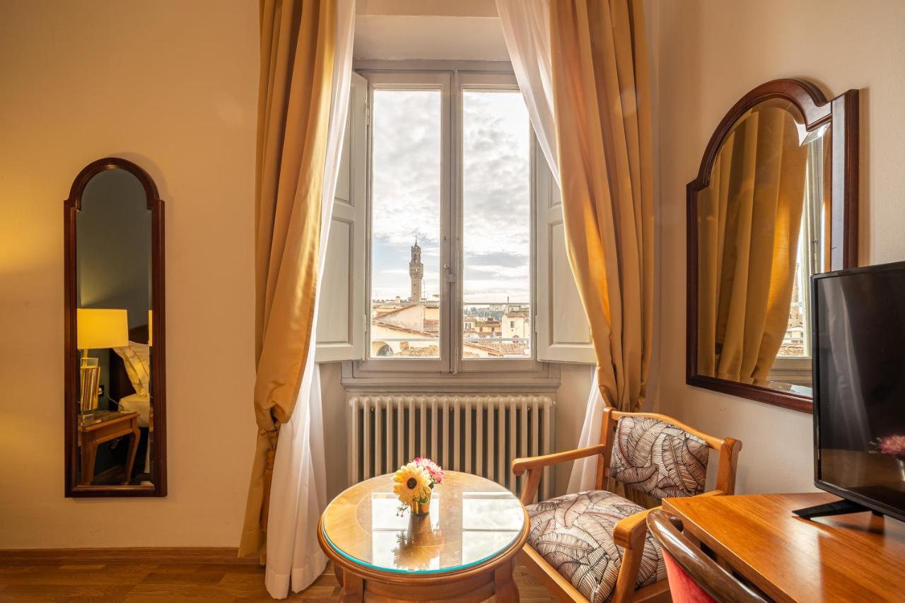 een woonkamer met een tafel en een raam bij Hotel Villani in Florence
