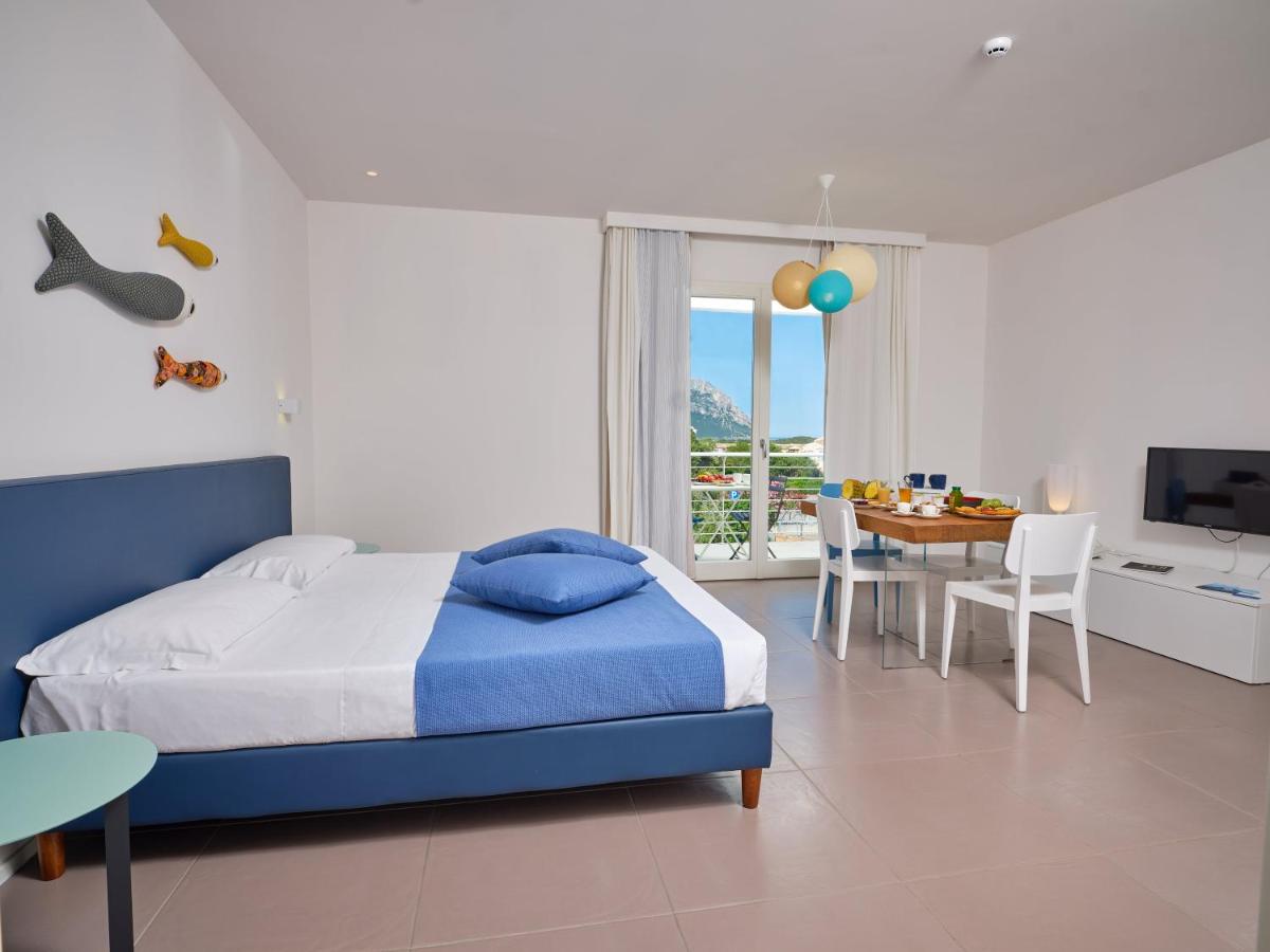 een slaapkamer met een blauw bed en een eetkamer bij Felix Hotels - Hotel Residence Porto San Paolo in Porto San Paolo +