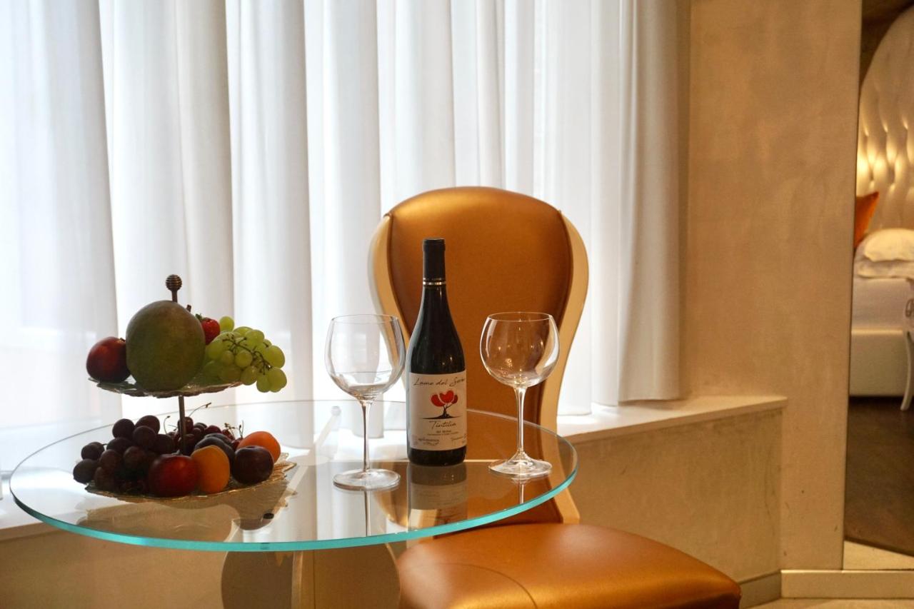 een glazen tafel met een fles wijn en wijnglazen bij Hotel Vespasiano in Rome