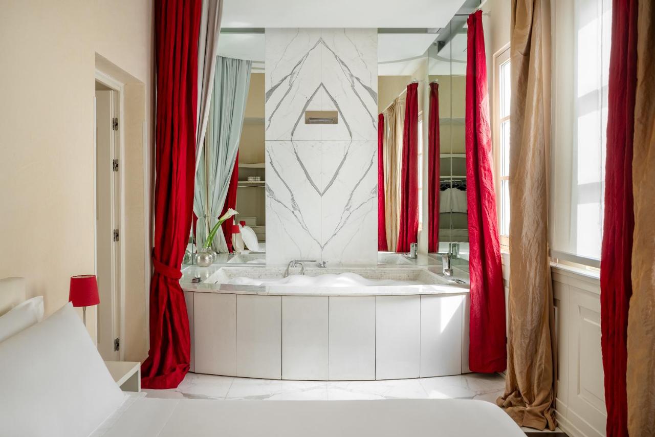 een badkamer met een wit bad en rode gordijnen bij Ricasoli Firenze Luxury Apartments | UNA Esperienze in Florence