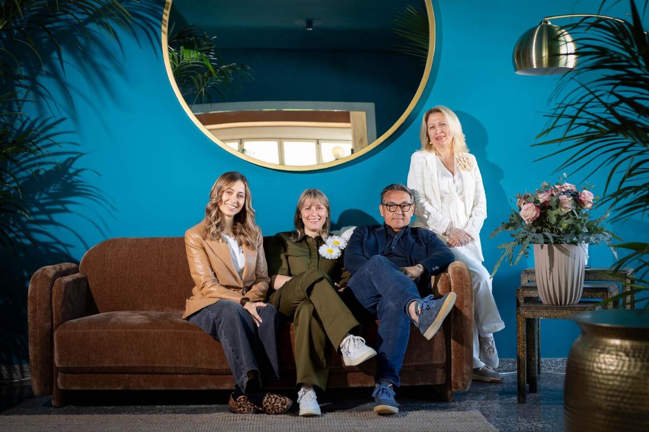 een groep mensen die op een bank voor een blauwe muur zitten bij Hotel Portofino in Lido di Jesolo