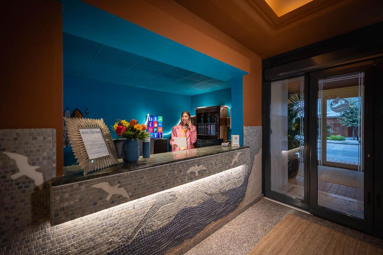 een vrouw staat aan een balie in de lobby van een hotel bij Hotel Portofino in Lido di Jesolo