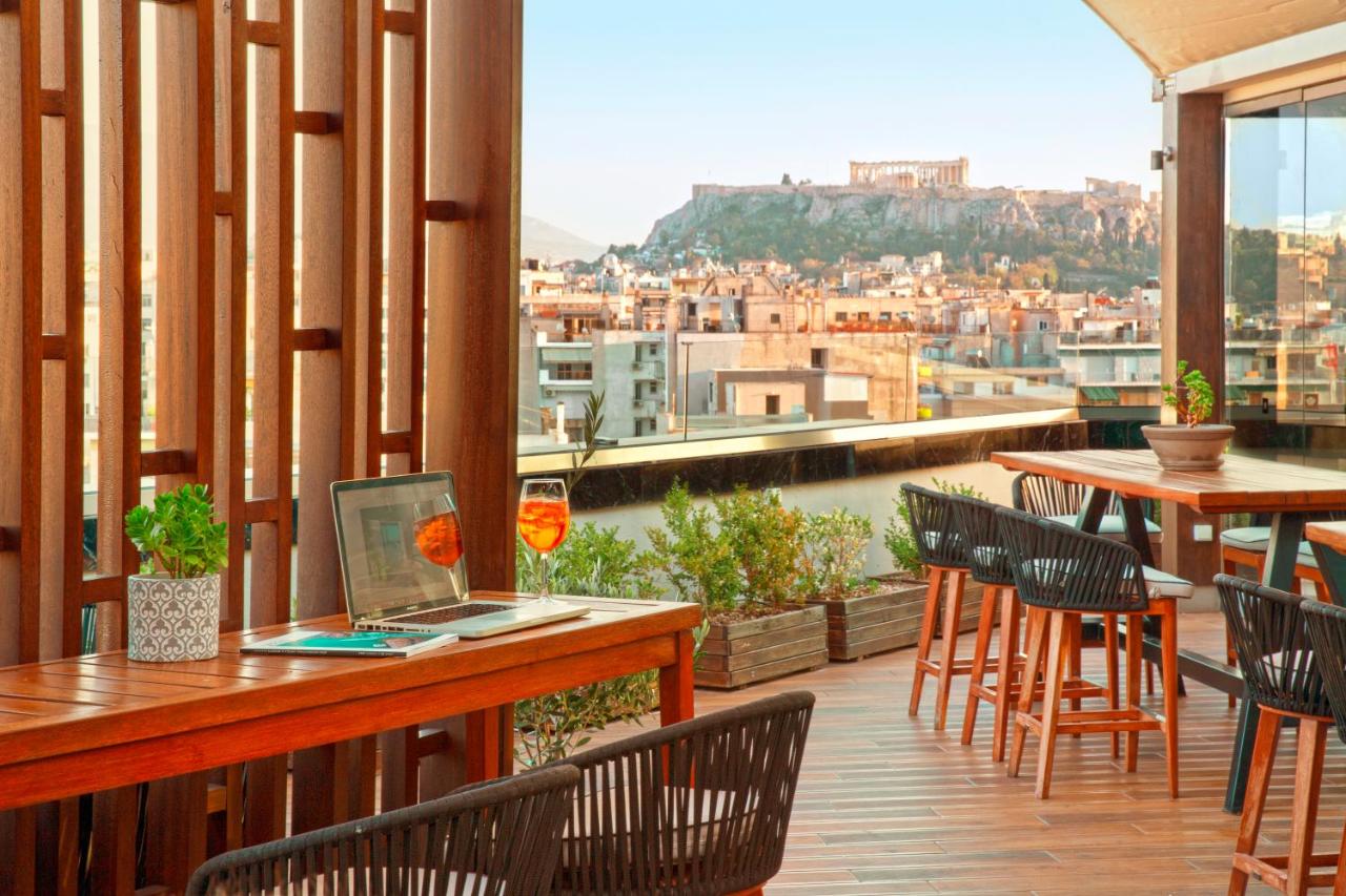 een balkon met een laptop op een tafel met stoelen bij Zeus Wyndham Grand Athens in Athene