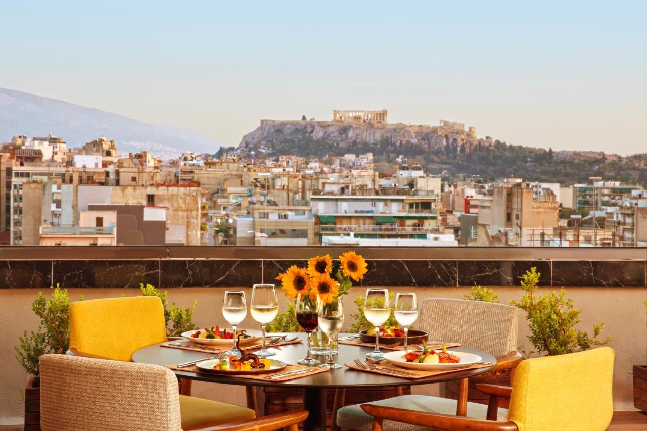 een tafel met borden met eten en wijnglazen bij Zeus Wyndham Grand Athens in Athene