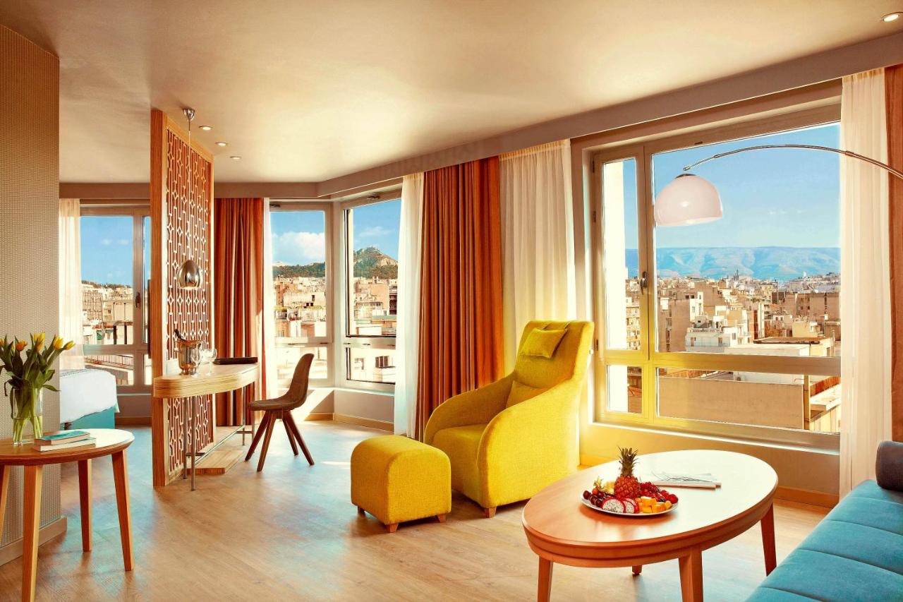 een woonkamer met een gele stoel en een tafel bij Zeus Wyndham Grand Athens in Athene