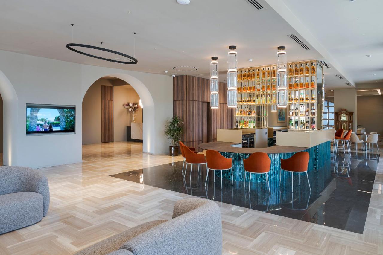een lobby met een bar met oranje stoelen bij Sant Alphio Garden Hotel & SPA in Giardini Naxos
