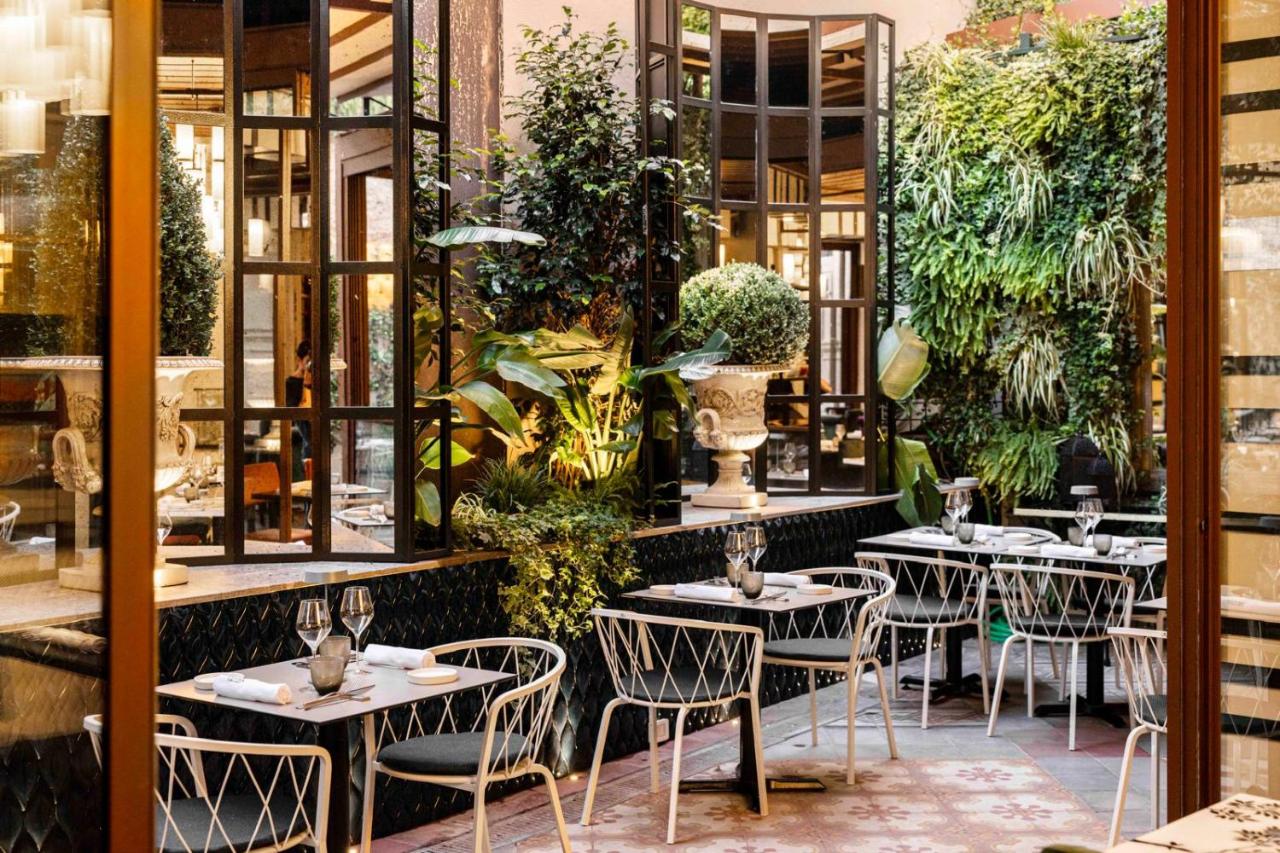 een restaurant met tafels, stoelen en planten bij Roma Luxus Hotel in Rome