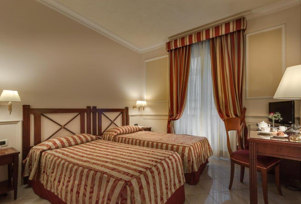 een hotelkamer met twee bedden en een bureau bij Palazzo Cardinal Cesi in Rome