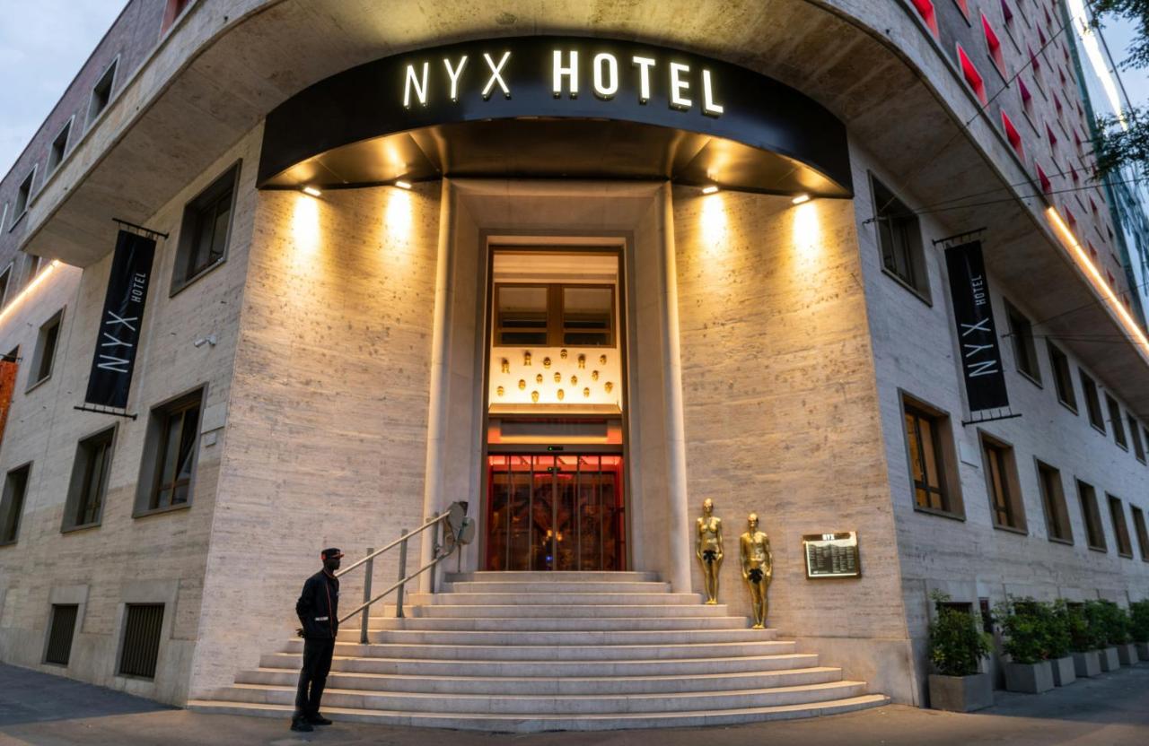 een man die voor een Myx Hotel staat bij NYX Hotel Milan by Leonardo Hotels in Milaan