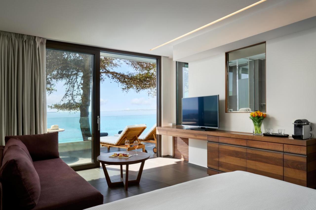 een slaapkamer met een bank, een televisie en een tafel bij White Rocks Hotel Kefalonia in Lassi