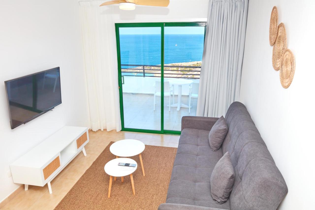 een woonkamer met een bank en uitzicht op de oceaan bij Hotel Chatur Palmera Mar in Amadores