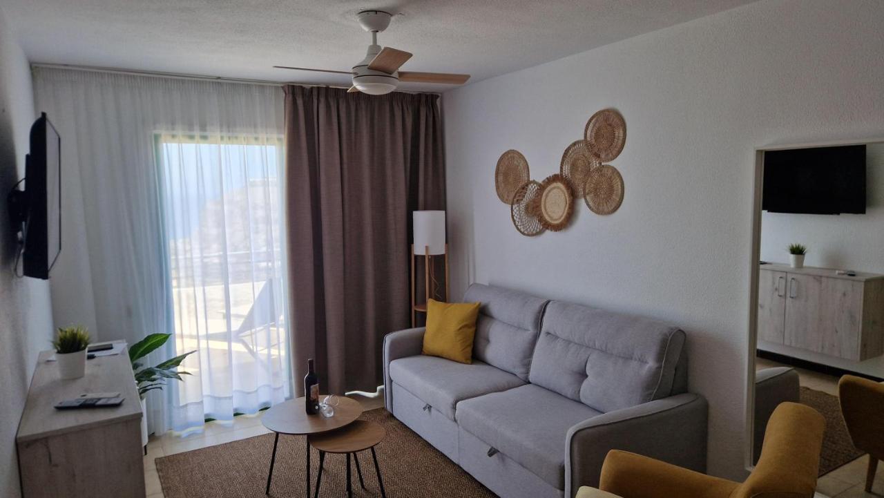 een woonkamer met een bank en een tafel bij Hotel Chatur Palmera Mar in Amadores