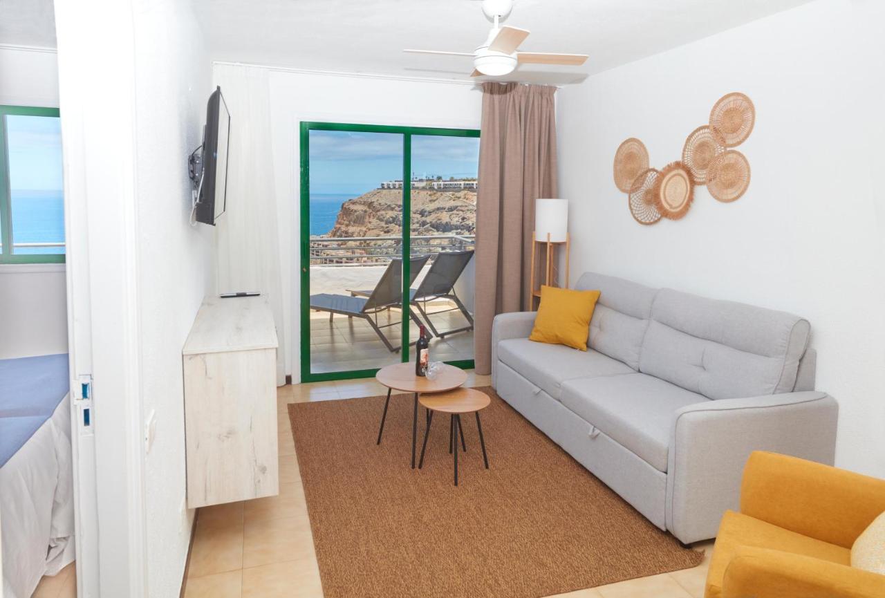 een woonkamer met een bank en uitzicht op de oceaan bij Hotel Chatur Palmera Mar in Amadores
