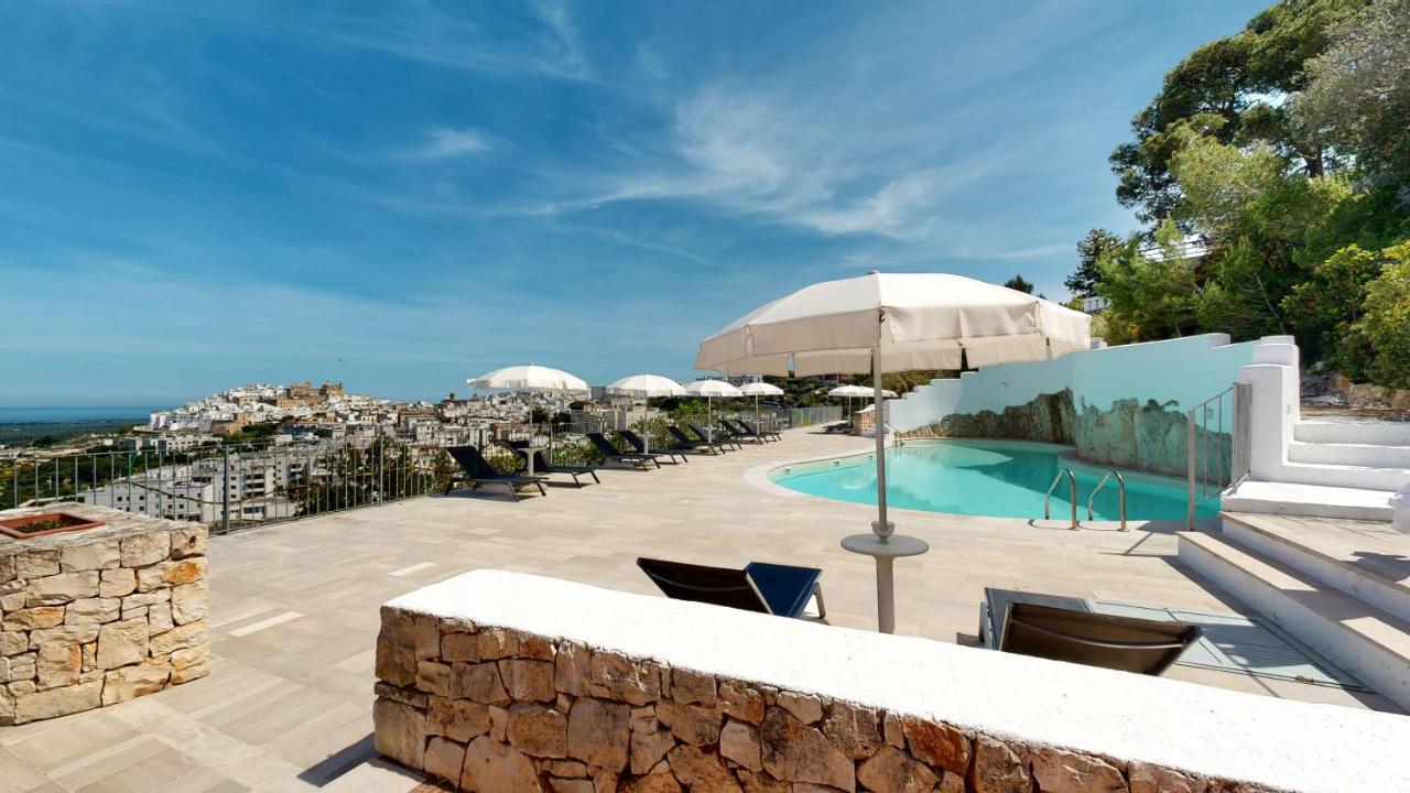 een zwembad met stoelen en parasols op een terras bij Monte Sarago Villas in Ostuni