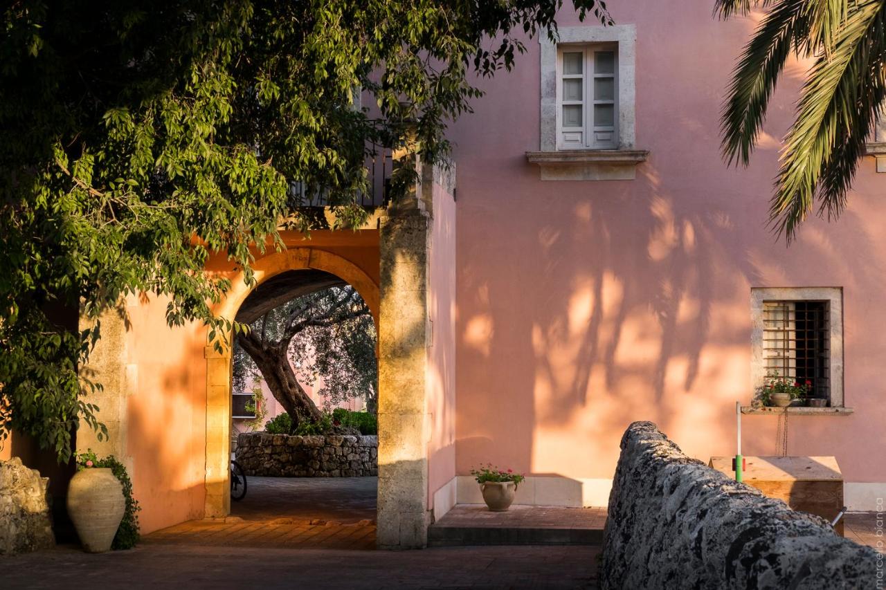 een ingang naar een roze gebouw met een boog. bij Masseria Degli Ulivi - Noto in Noto