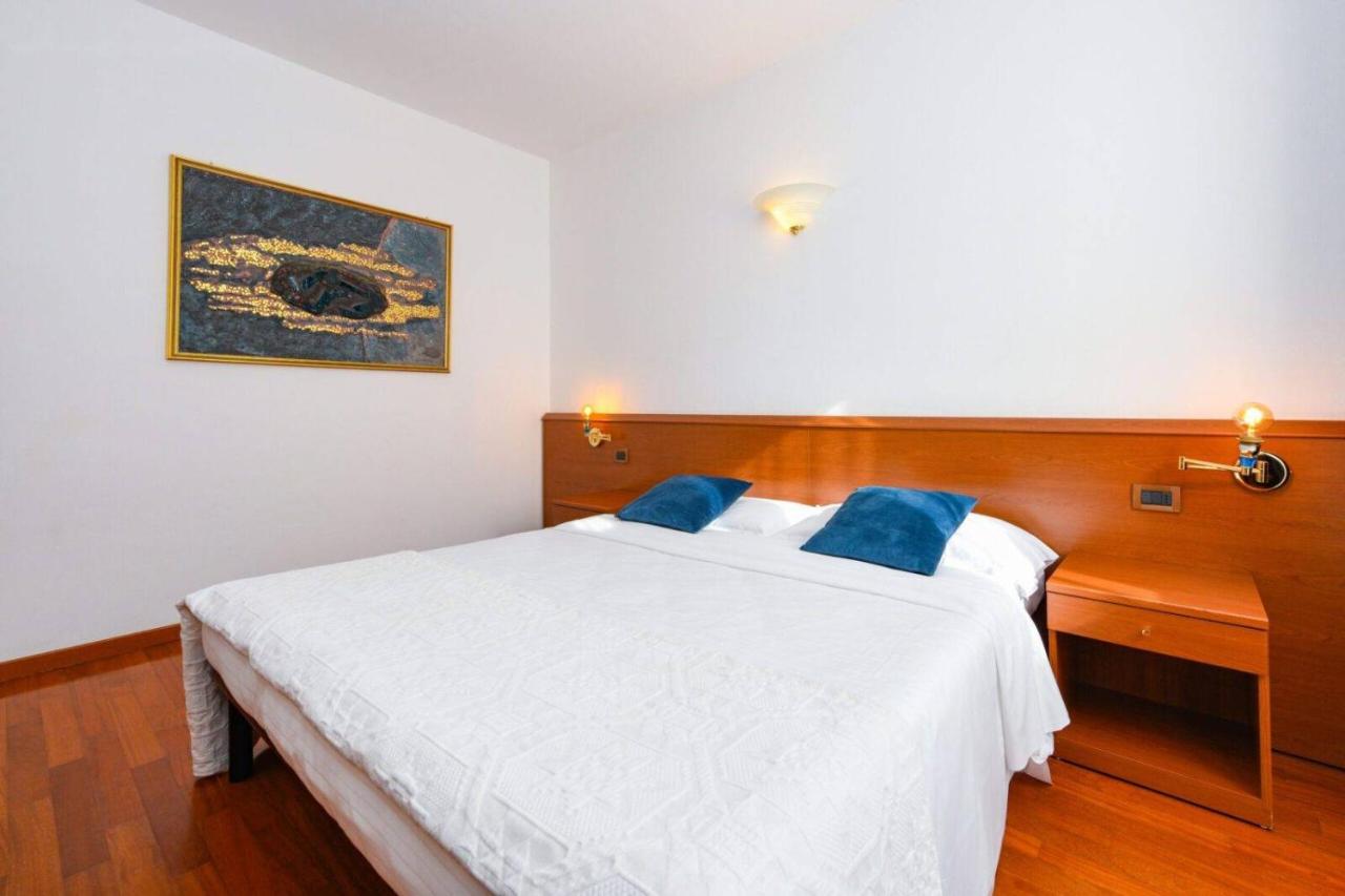 een slaapkamer met een groot wit bed met blauwe kussens bij Hotel New Genziana in Altavilla Vicentina