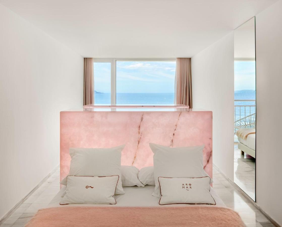 een witte slaapkamer met een roze hoofdbord en kussens bij Hotel Aromar in Platja  d'Aro