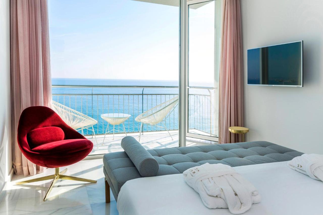 een slaapkamer met een bank en een stoel en een balkon bij Hotel Aromar in Platja  d'Aro