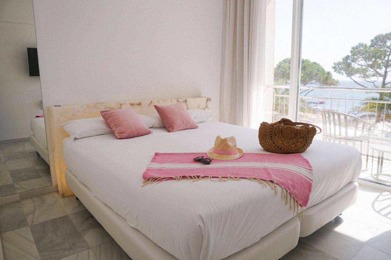 een slaapkamer met een wit bed, roze kussens en een raam bij Hotel Aromar in Platja  d'Aro