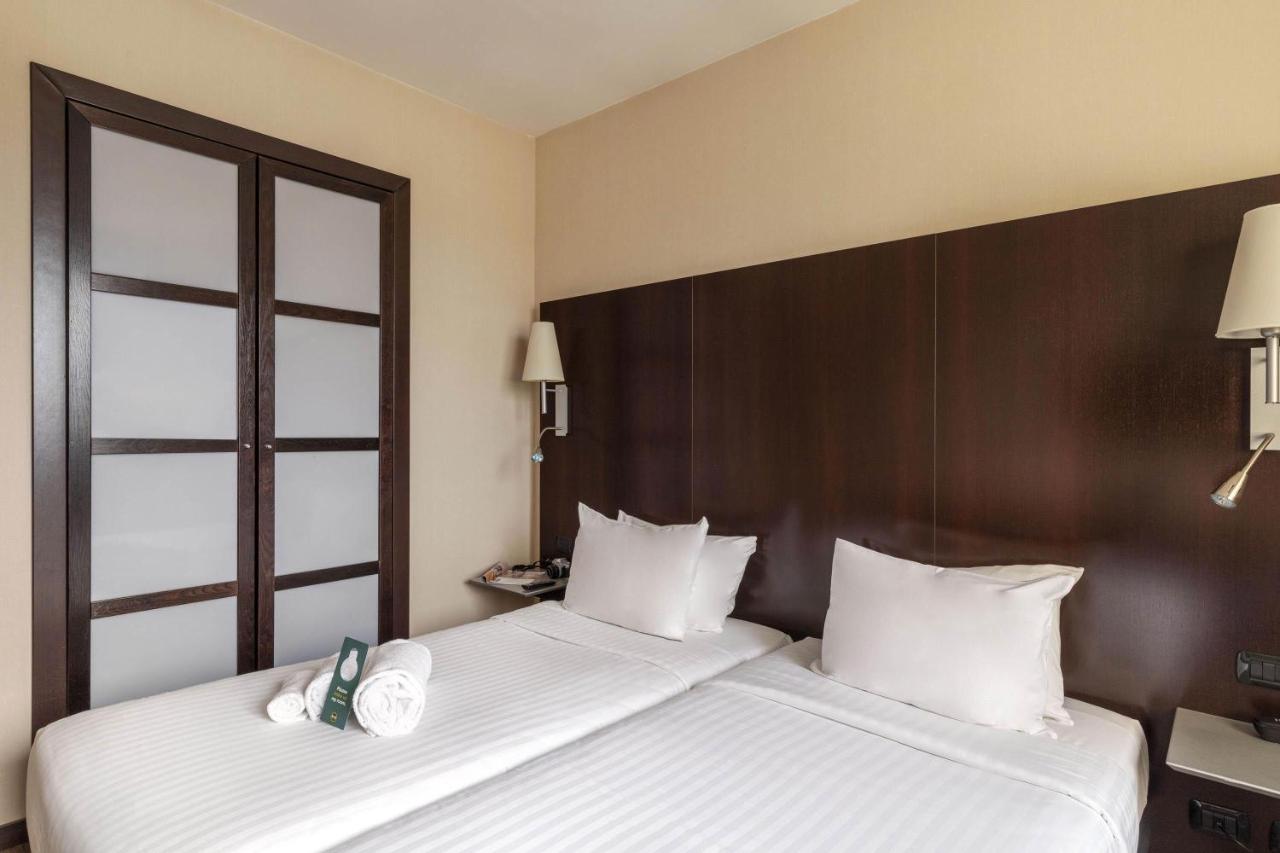 een hotelkamer met twee bedden met witte kussens bij B&B Hotel Arezzo in Arezzo