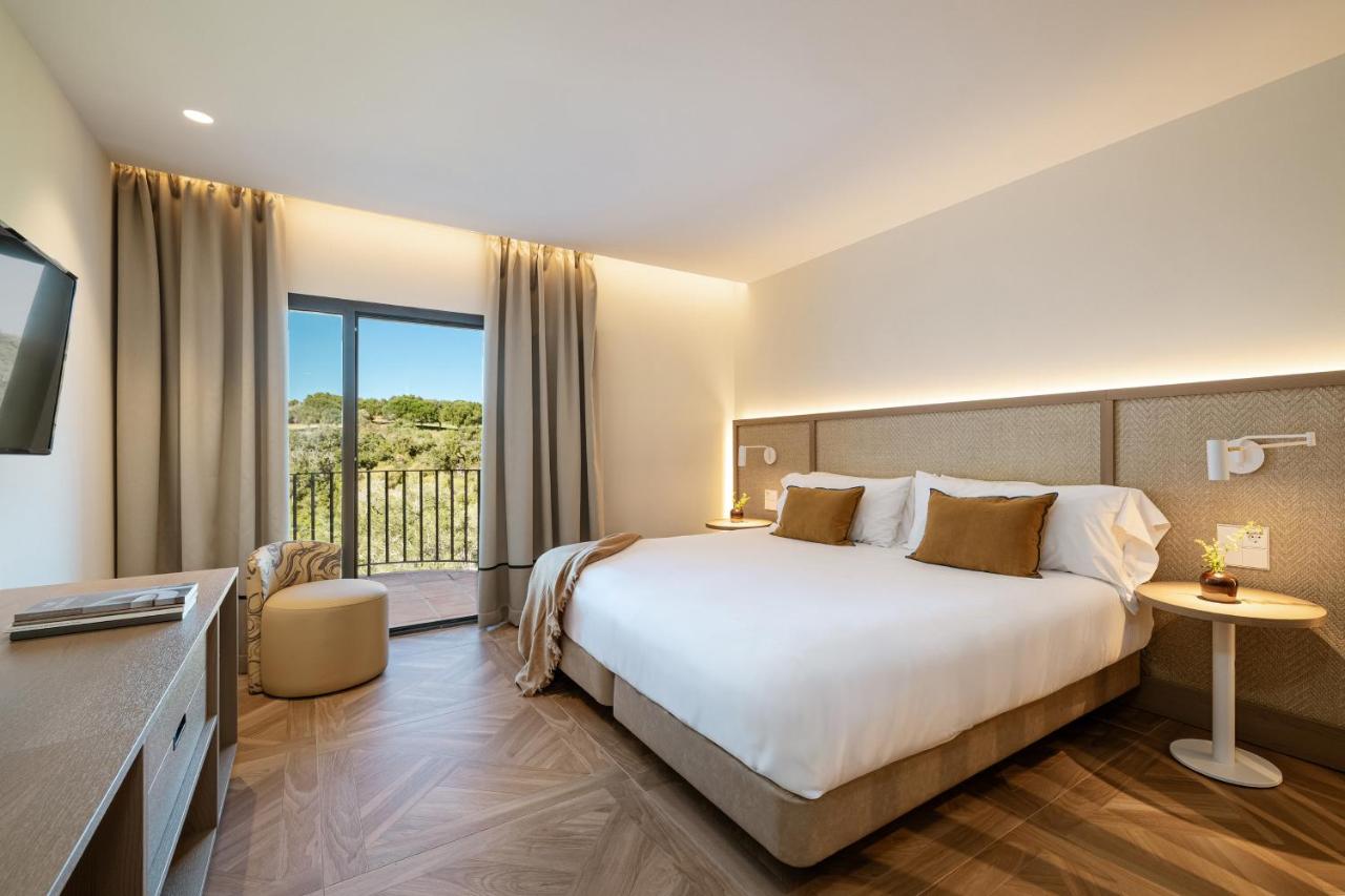 een hotelkamer met een bed en een balkon bij Hotel Encinar de Sotogrande in Sotogrande