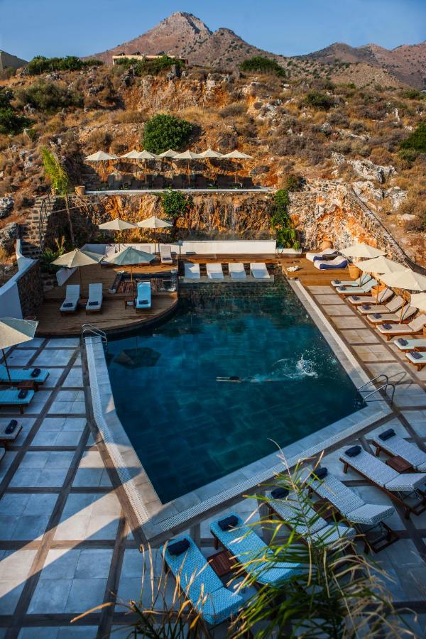 een zwembad met ligstoelen en een berg op de achtergrond bij Elounda Orama by GHH in Elounda
