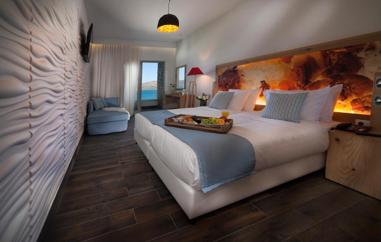 een slaapkamer met een groot bed waarop een dienblad met fruit staat bij Elounda Orama by GHH in Elounda
