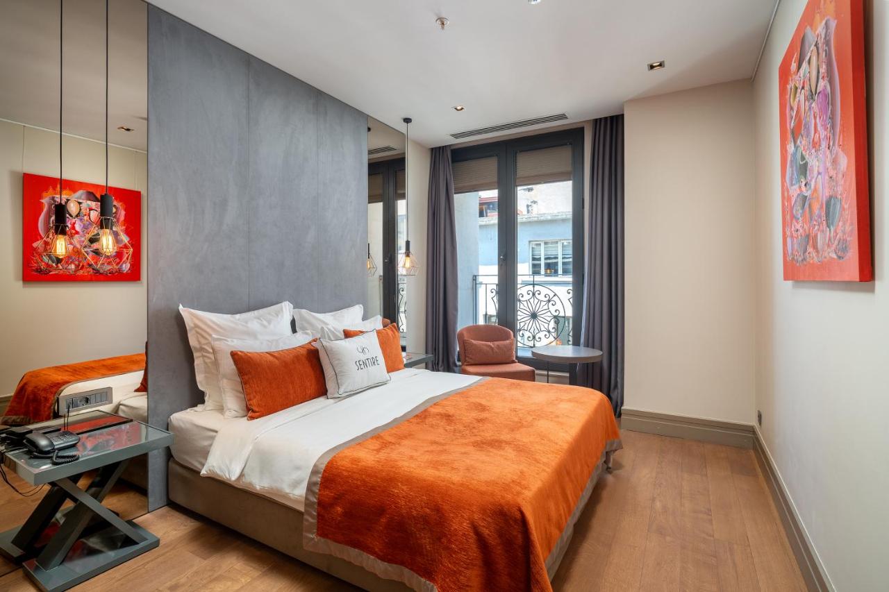 een slaapkamer met een groot bed met een oranje deken bij Sentire Hotels & Residences Taksim in Istanbul