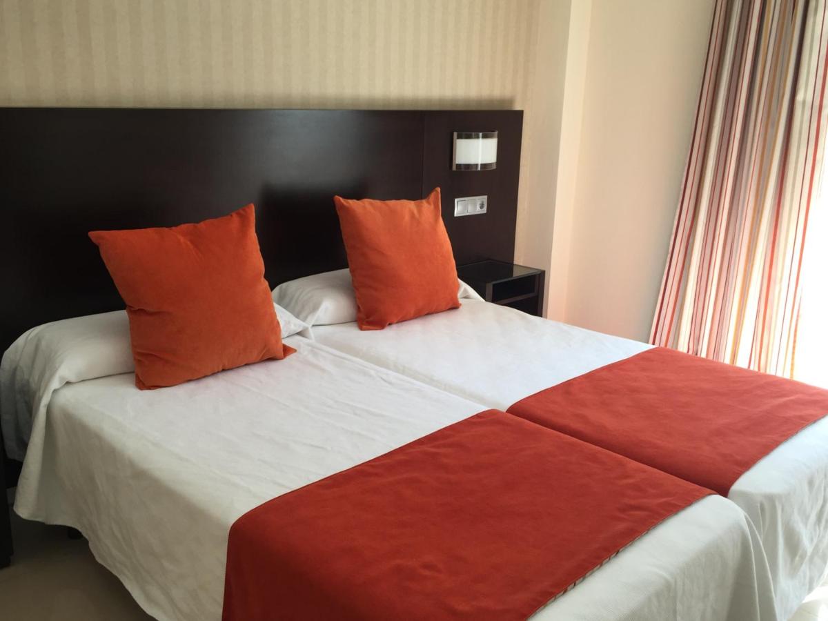 een slaapkamer met een groot bed met oranje kussens bij Hotel Pradillo Conil in Conil de la Frontera