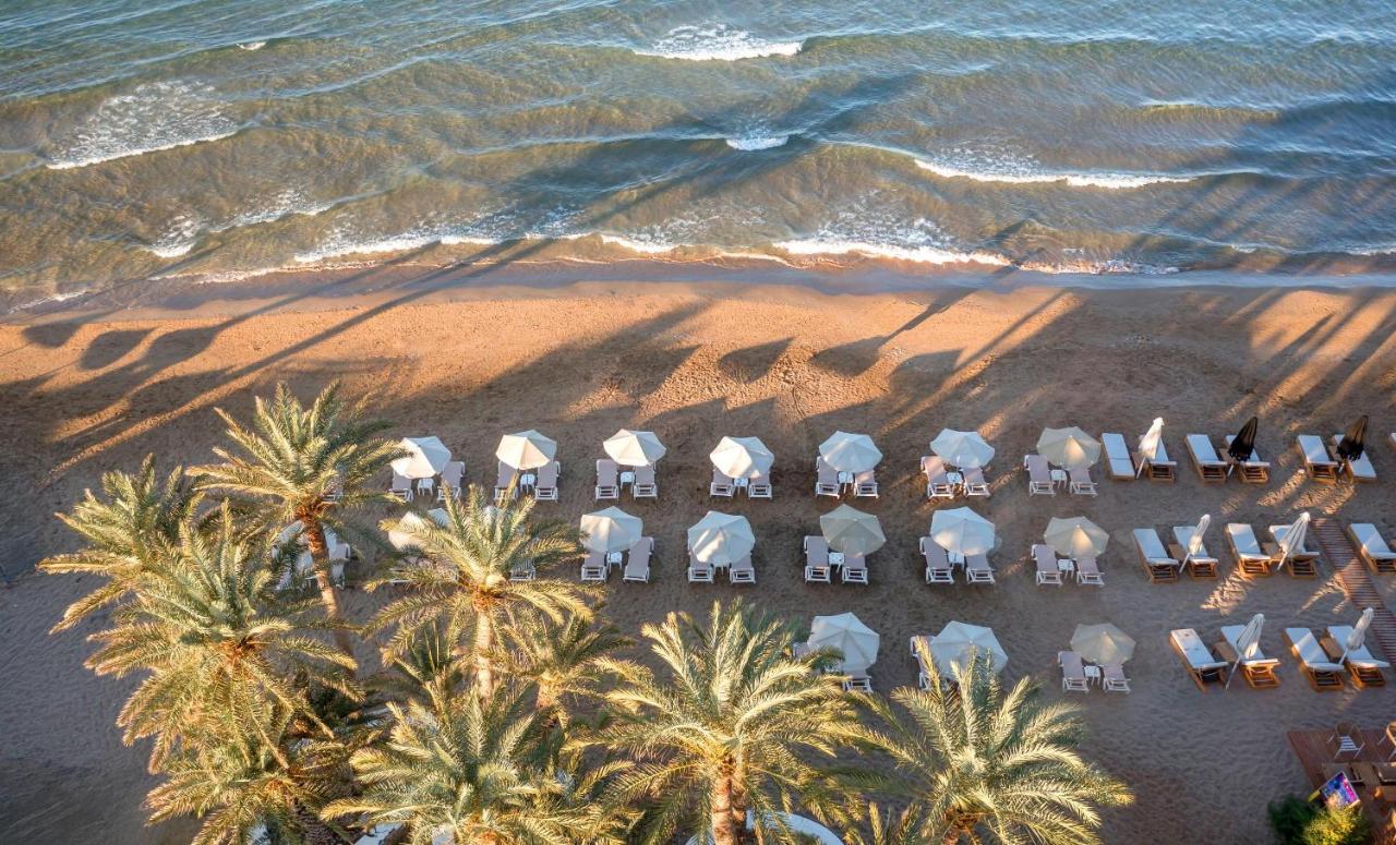 Een luchtfoto van een strand met stoelen en palmbomen. bij Zeus Hotels Palm Beach in Stalida