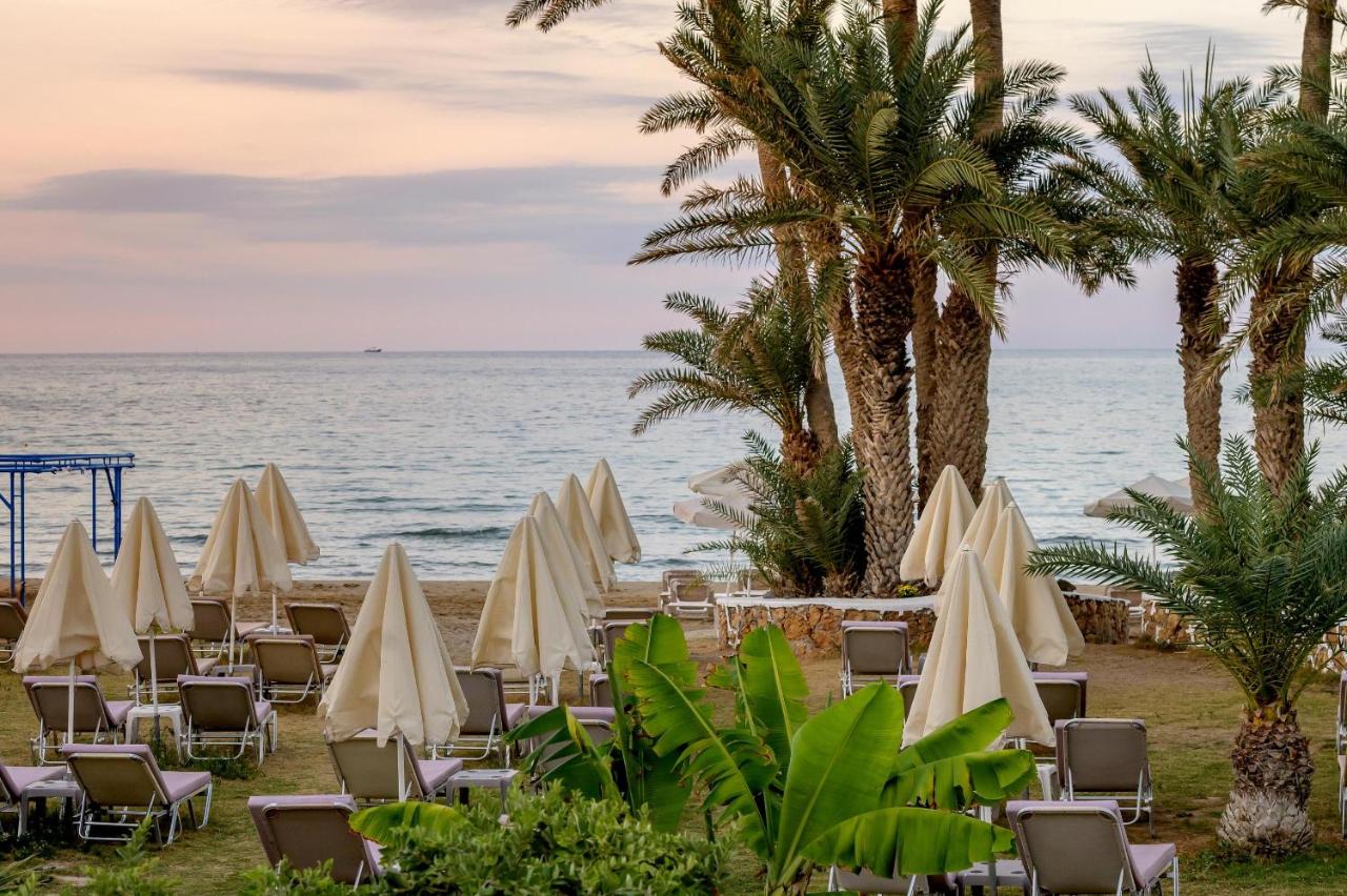 een strand met stoelen en parasols en de oceaan bij Zeus Hotels Palm Beach in Stalida