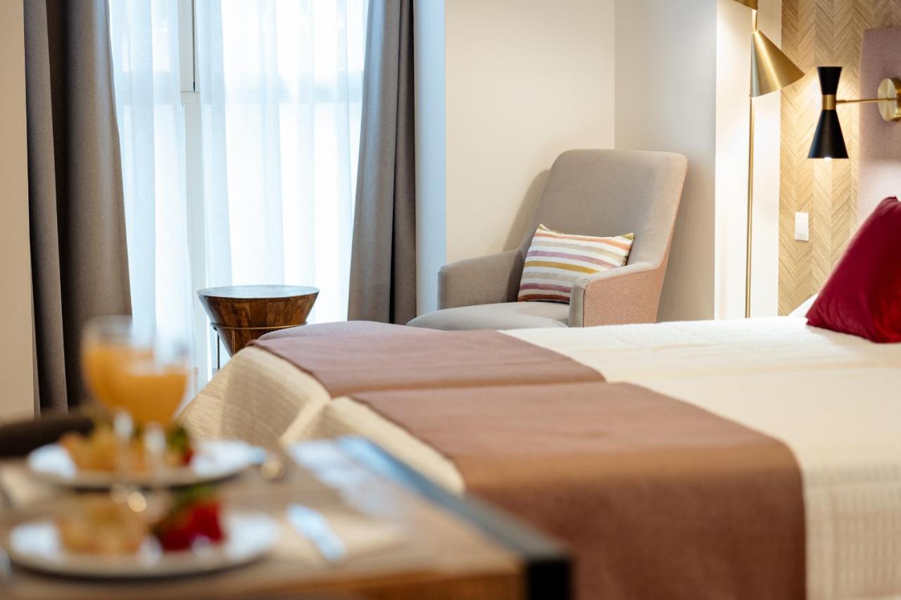 een hotelkamer met twee bedden en een stoel bij Apartamentos Debambú in Málaga