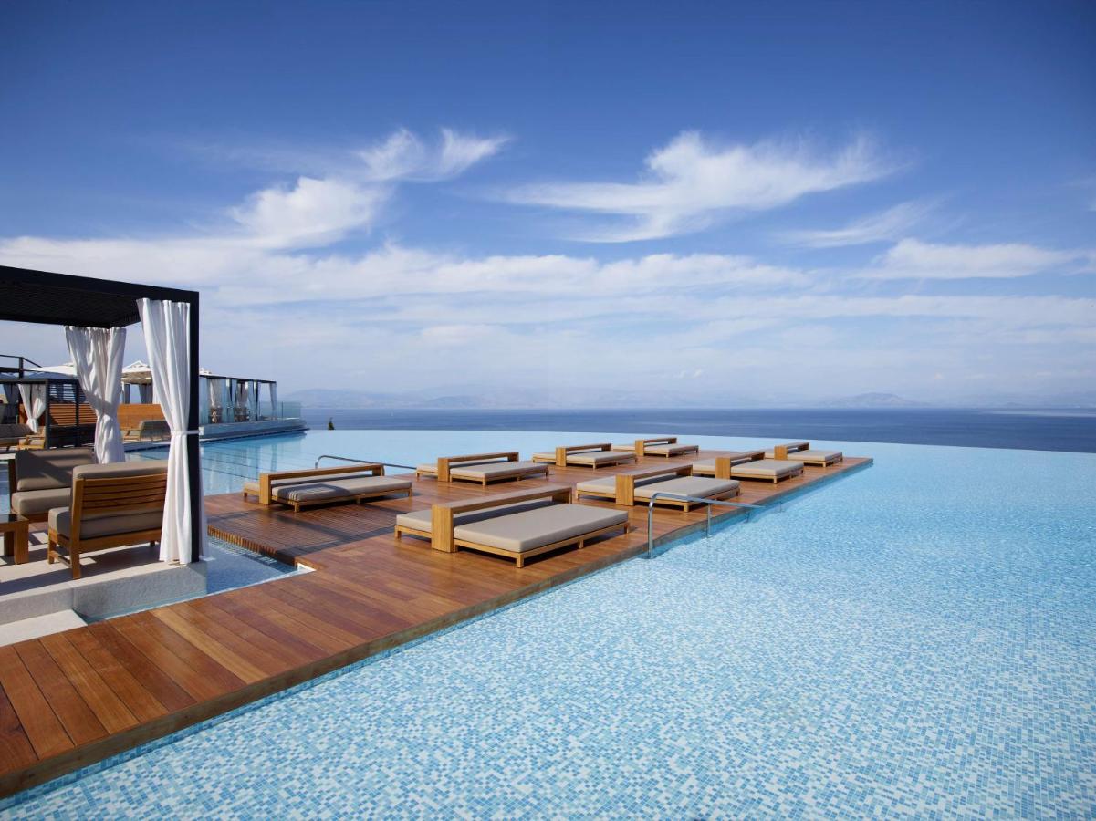 een zwembad met banken en stoelen in het water bij Angsana Corfu Resort & Spa in Benitses