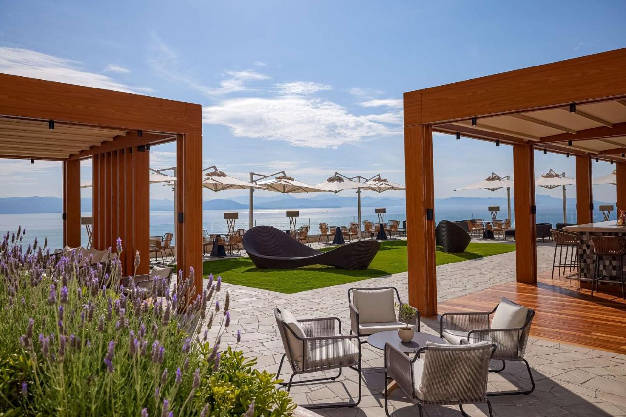 een terras met stoelen en tafels en uitzicht op de oceaan bij Angsana Corfu Resort & Spa in Benitses