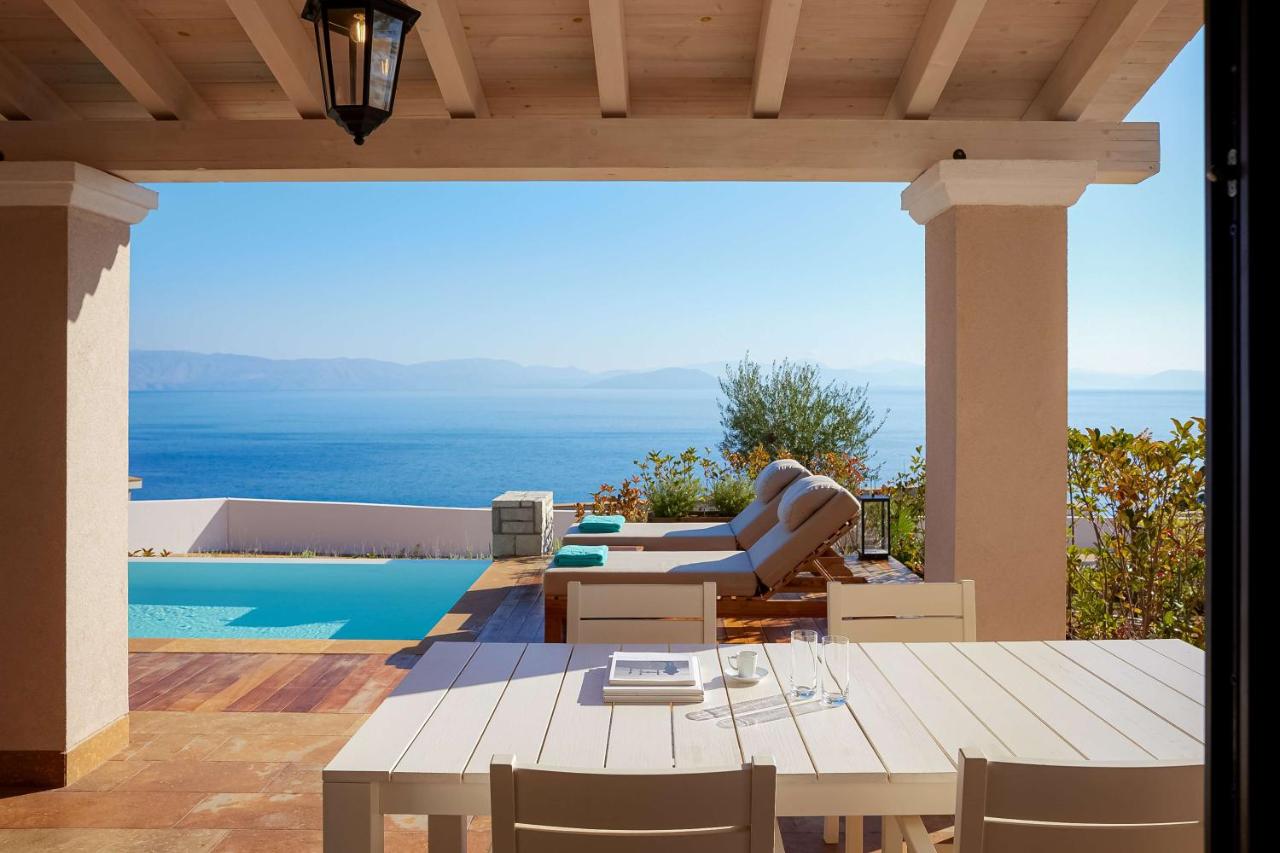 een terras met een tafel en stoelen en een zwembad bij Angsana Corfu Resort & Spa in Benitses
