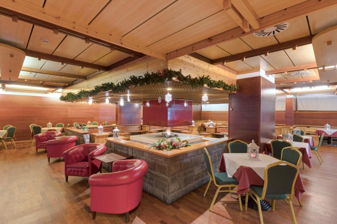 een restaurant met een bar met tafels en stoelen bij Hotel Club Regina E Fassa in Mazzin +50 foto's