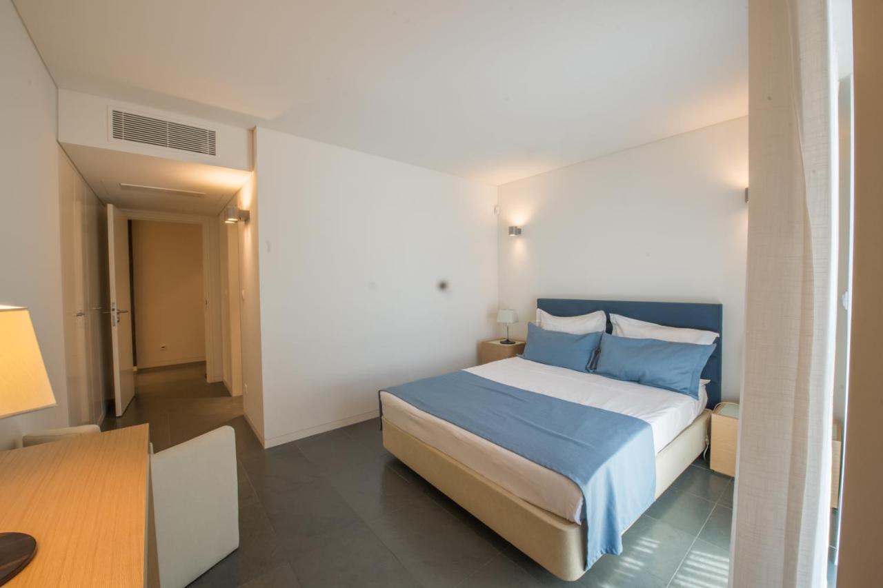 een slaapkamer met een groot bed met blauwe lakens bij Troia Residences - Apartamentos Ácala in Troia