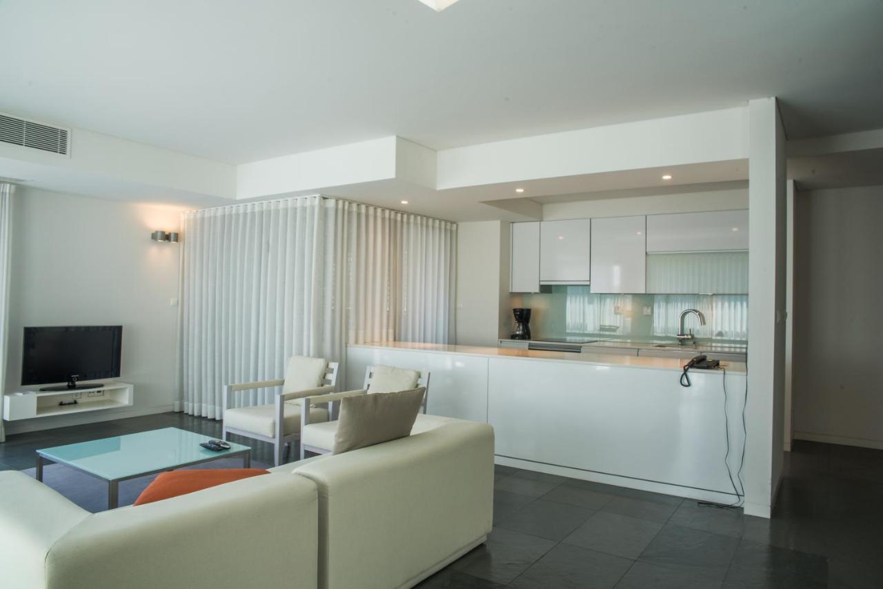 een woonkamer met een witte bank en een keuken bij Troia Residences - Apartamentos Ácala in Troia
