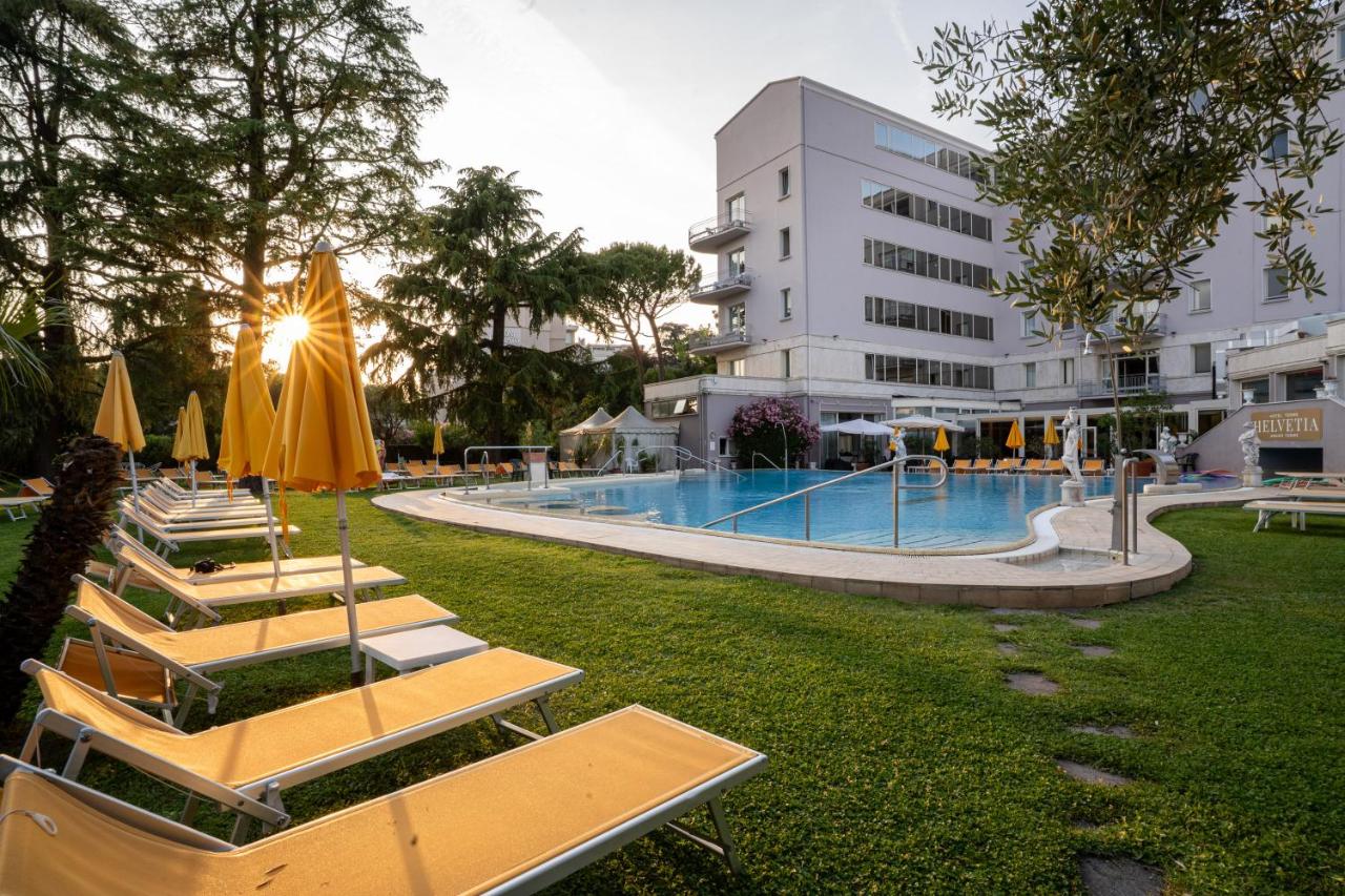 een hotel met een zwembad met tafels en parasols bij Hotel Terme Helvetia in Abano Terme