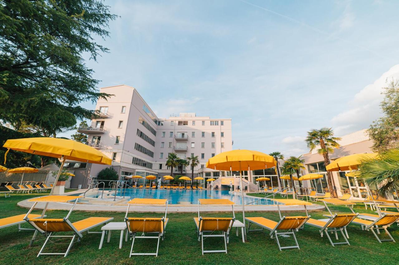 een zwembad met stoelen en parasols voor een gebouw bij Hotel Terme Helvetia in Abano Terme