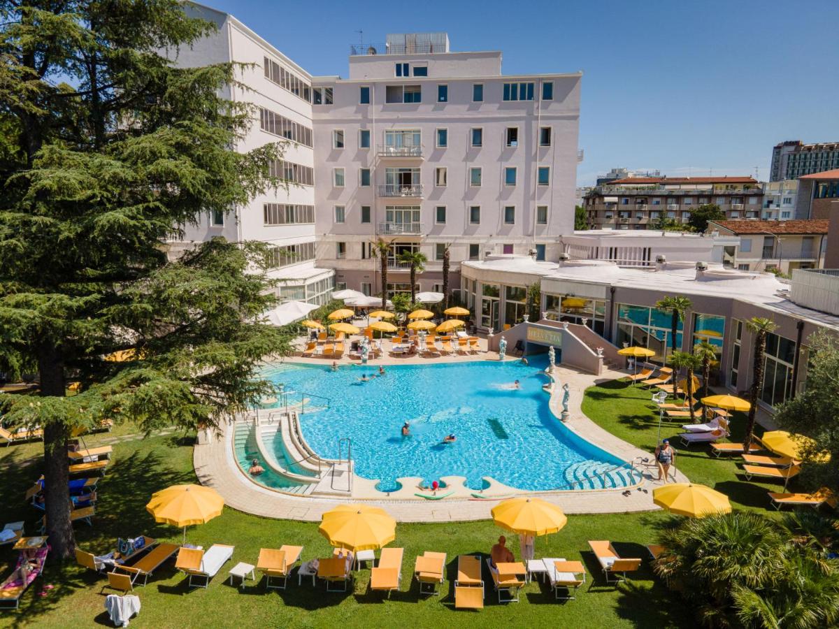 een groot zwembad met gele parasols en ligstoelen bij Hotel Terme Helvetia in Abano Terme