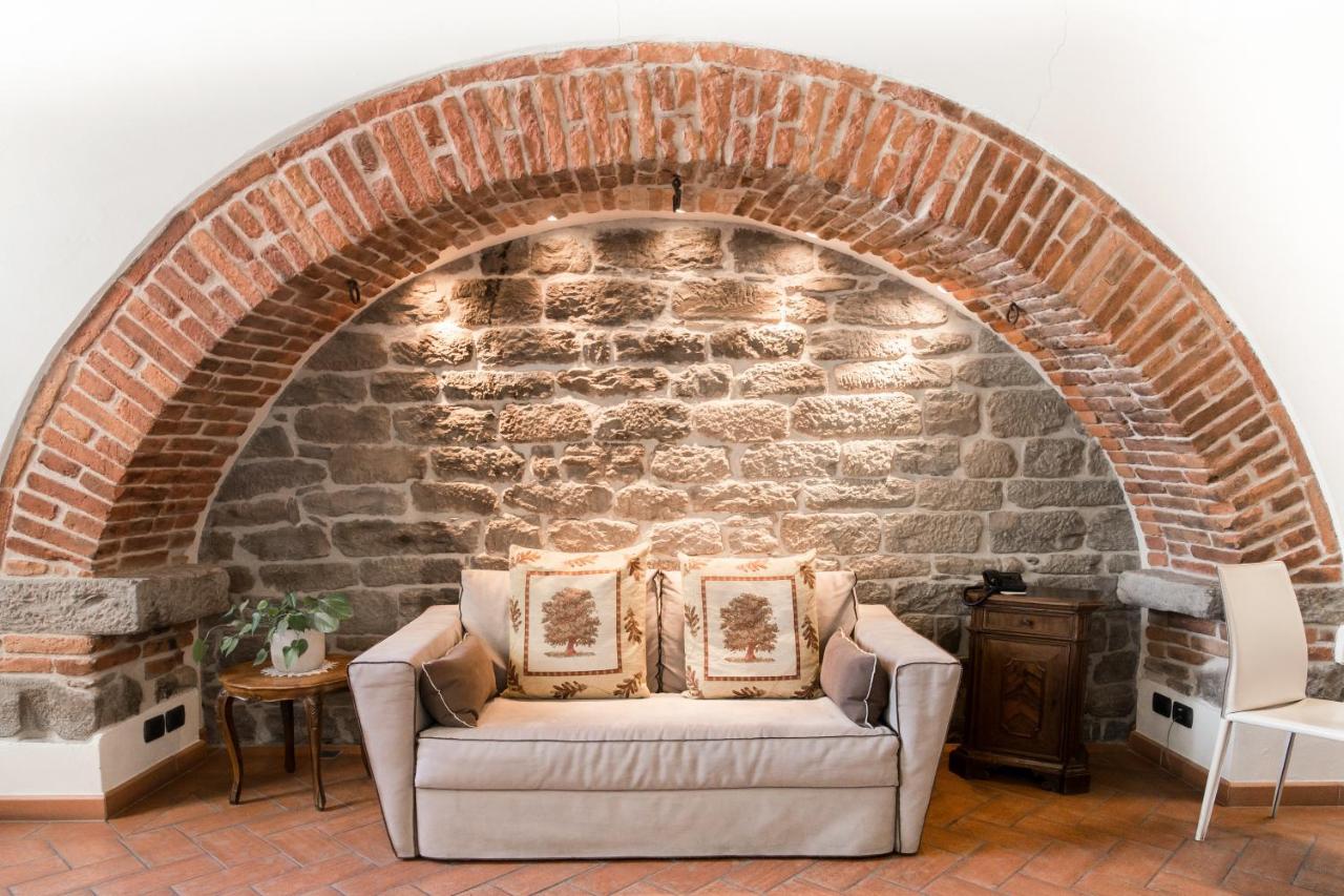 een woonkamer met een bakstenen muur en een bank bij La Corte Del Re Suite & Rooms Arezzo in Arezzo