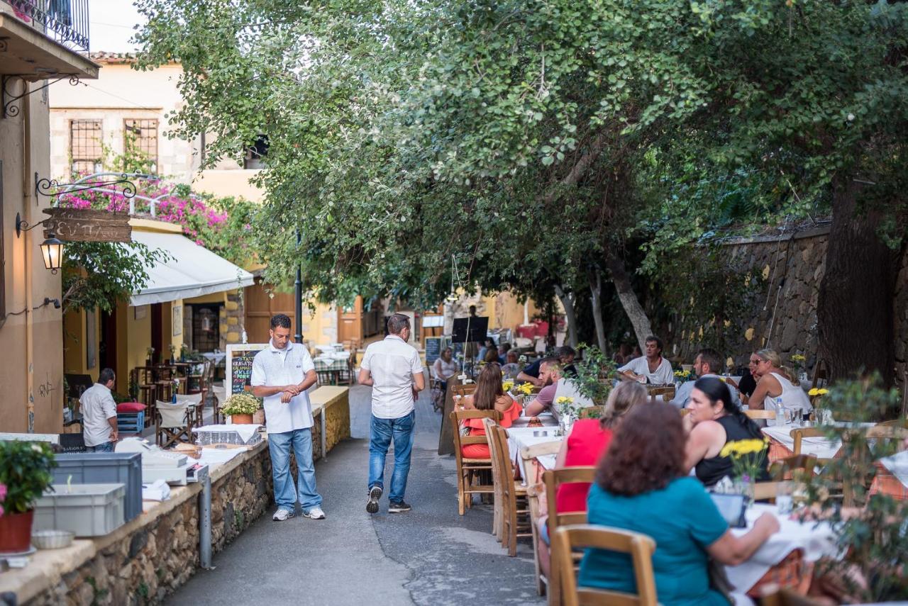 een groep mensen die aan tafels in een tuin zitten bij Elia Portou Due in Chania