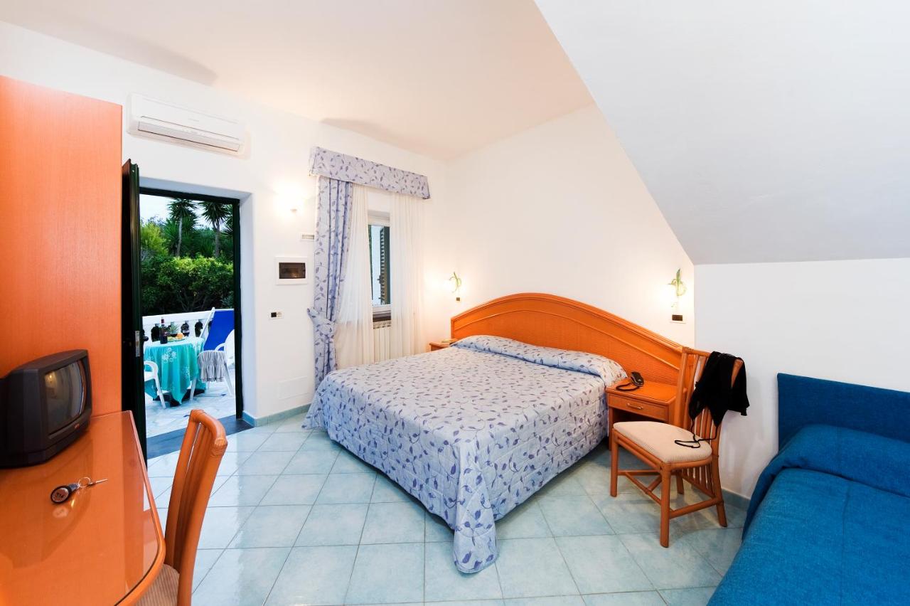 een slaapkamer met een bed en een blauwe bank bij Park Hotel Terme Mediterraneo in Forio d'Ischia