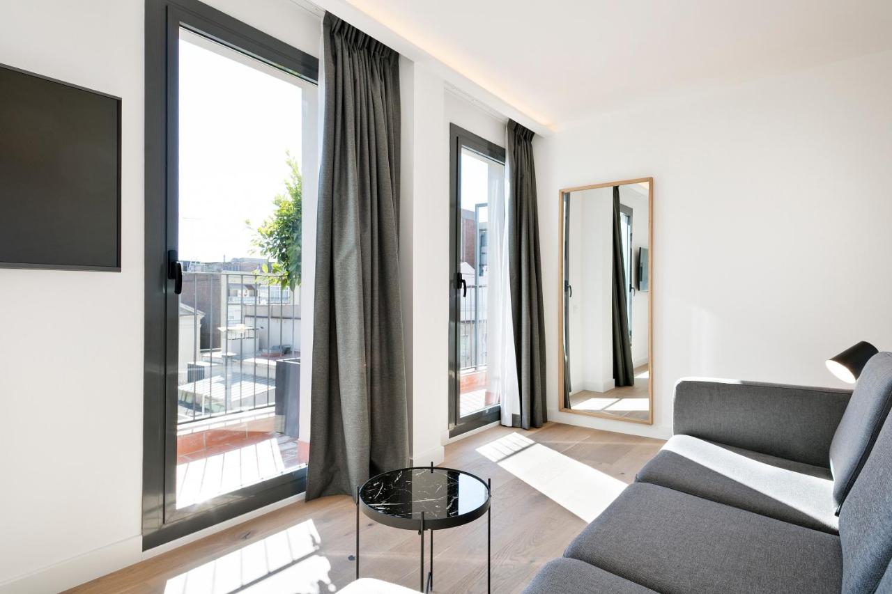 een woonkamer met een bank en grote ramen bij Murmuri Residence Mercader in Barcelona